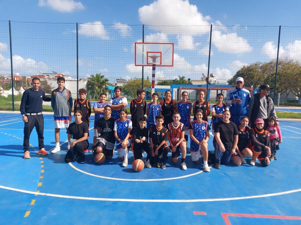 Groupe de jeunes joueurs de l'ASEK avec leur entraîneur sur le terrain à Kénitra